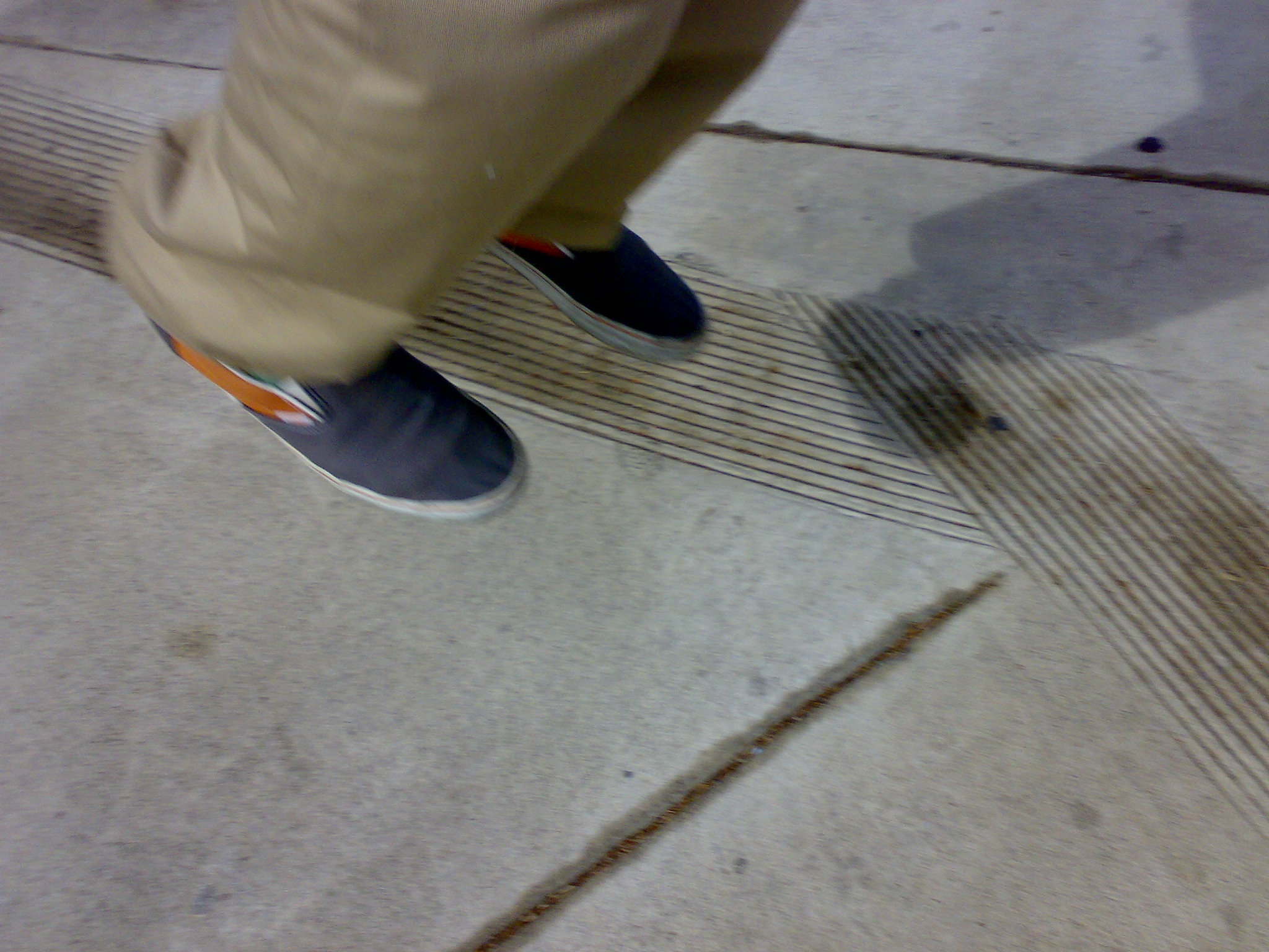 person wearing khaki and blue shoes on sidewalk