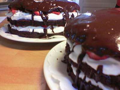 two cakes on plates covered in frosting and chocolate