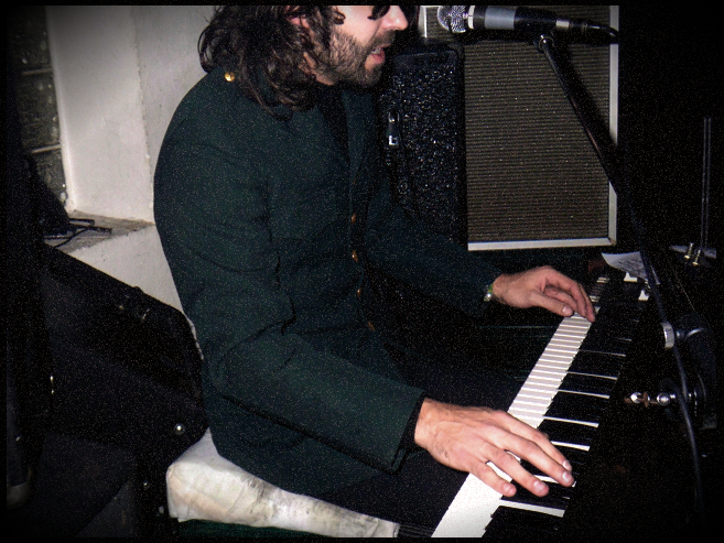 there is a male in a green shirt sitting at a piano and playing