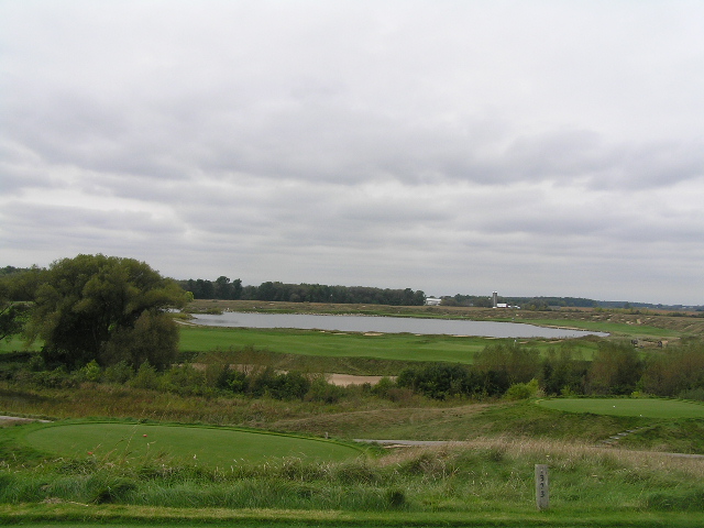 a view of a golf course and water on a cloudy day