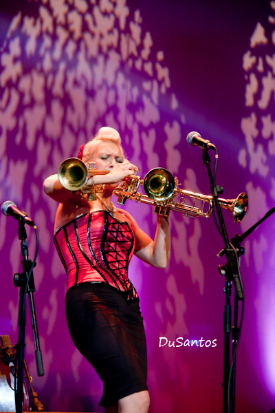 woman with blonde hair playing on musical instrument in front of microphones