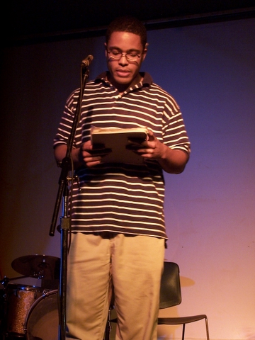 a man standing on stage with a microphone and holding soing
