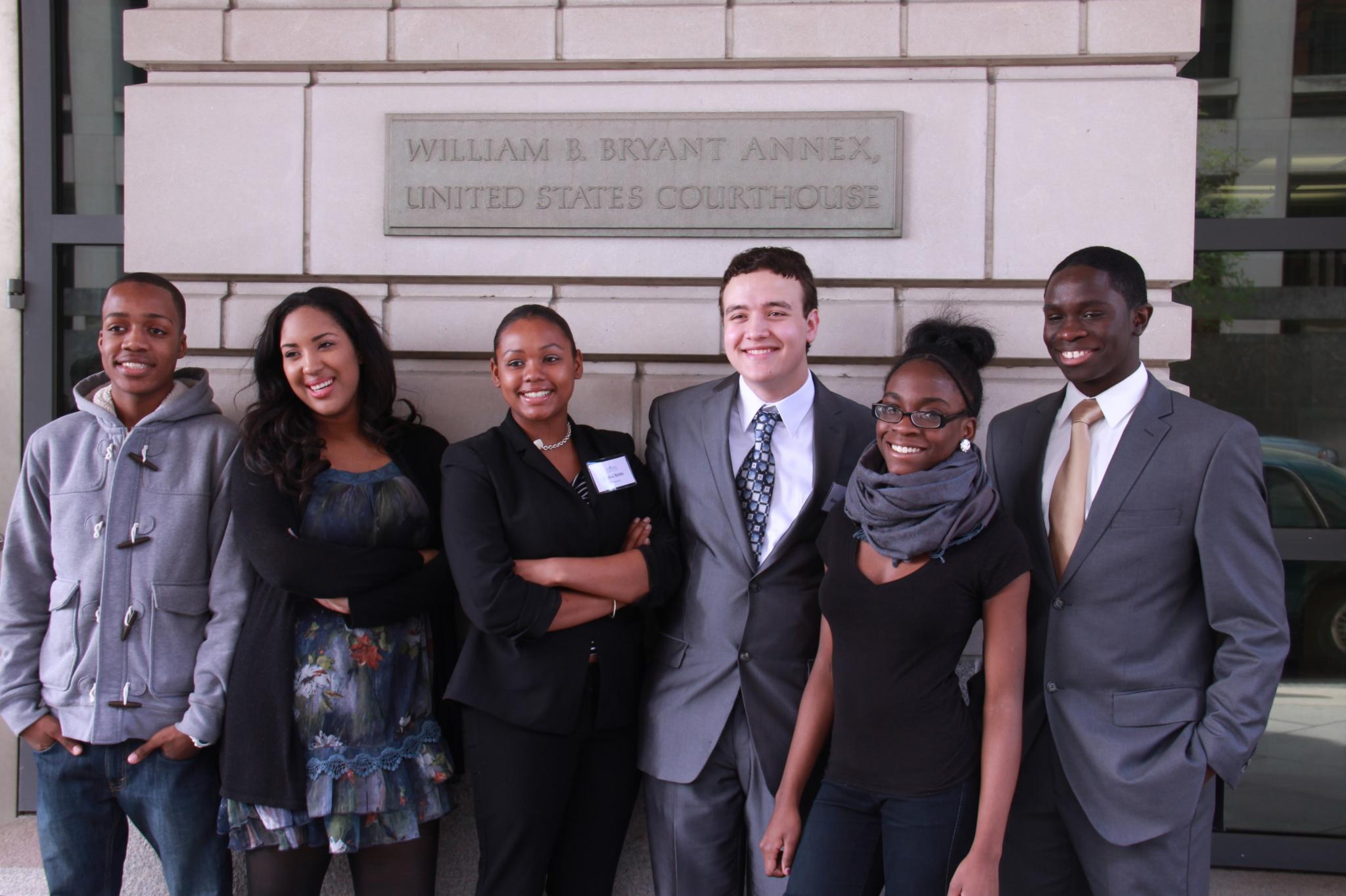 seven people are posing in front of a building