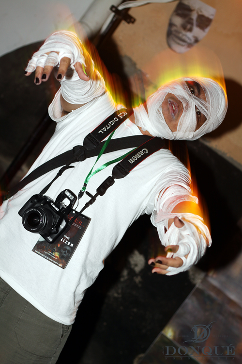 man wearing white plastic face paint, a camera and a shirt