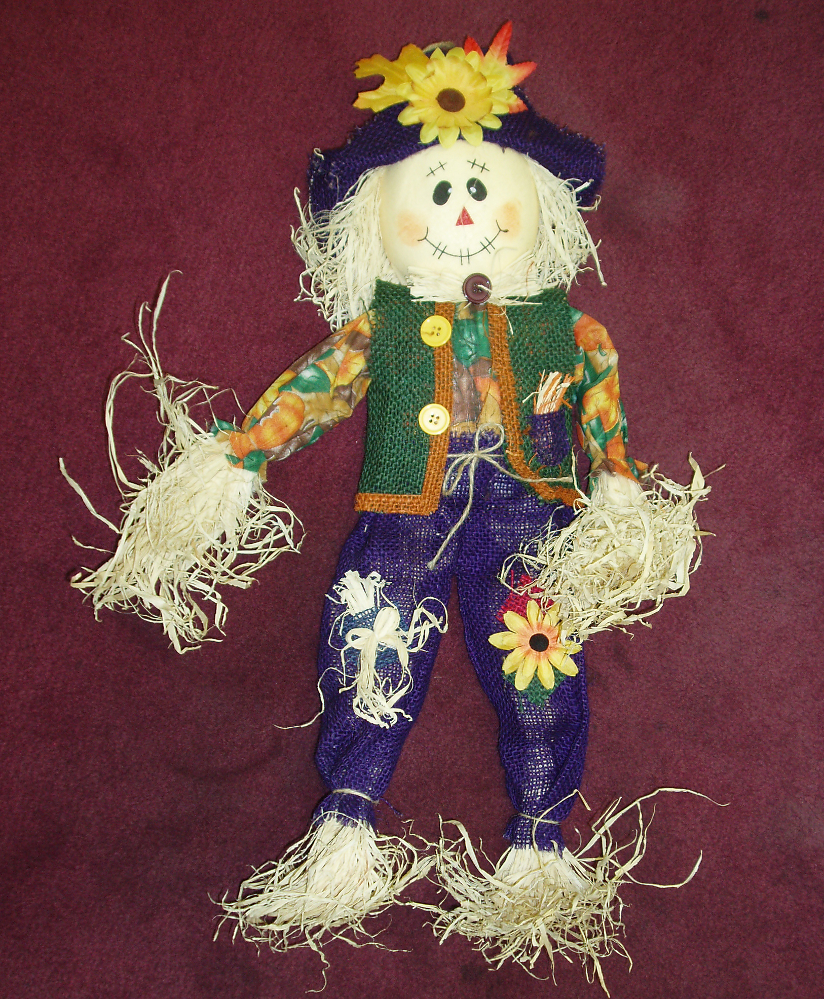 a scarecrow has a colorful hat and orange flower in it