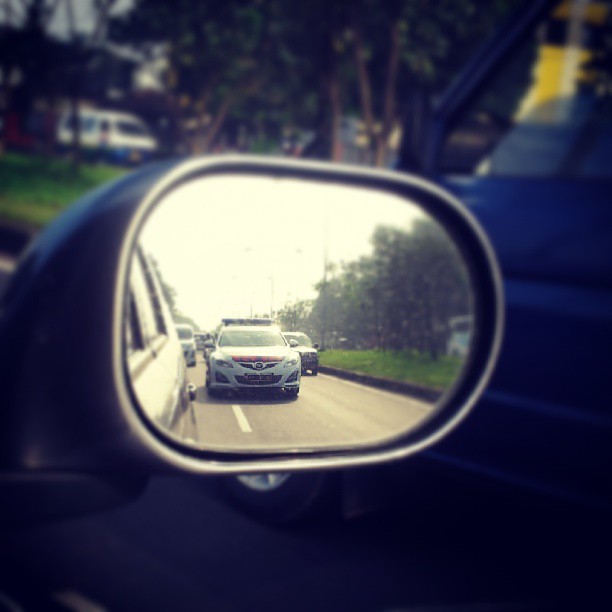 a car in the back mirror next to another vehicle on a street