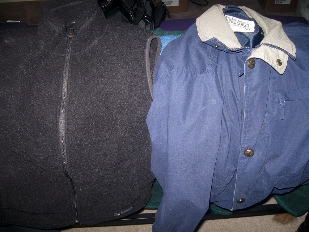 two jackets hang on a rack on a wall