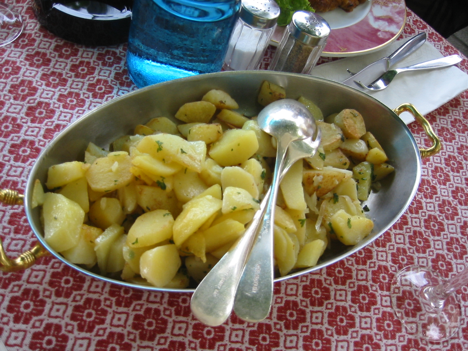 a bowl full of potato sits on a table with silverware