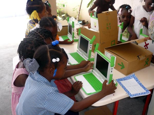group of children playing with green laptops in an assembly line