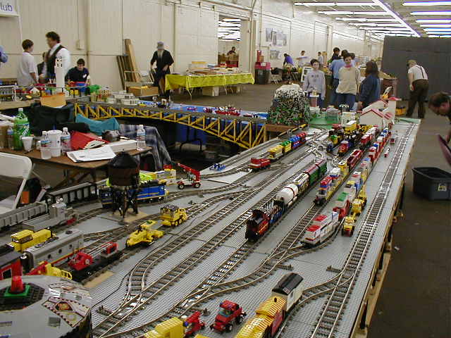 a group of people standing at a booth with a large model train set on display