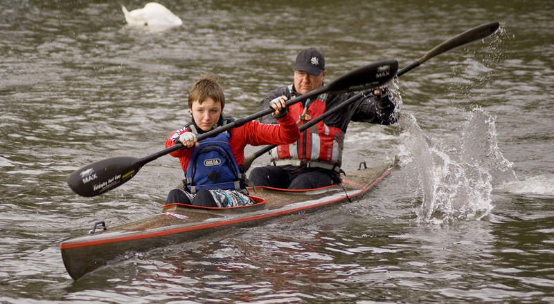 a man and boy riding in the back of a canoe