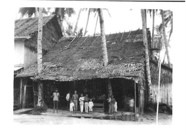 a vintage po of people standing outside of a hut