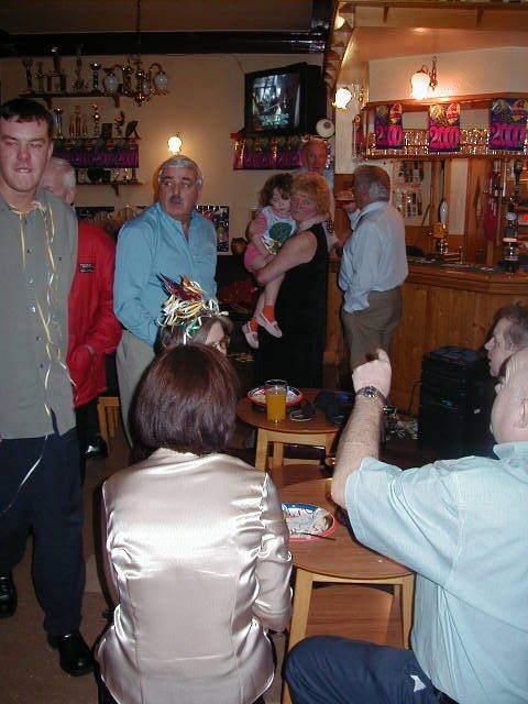 a group of people are standing and sitting in a pub