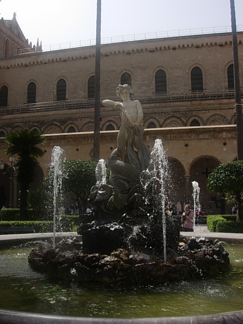 a fountain with water and statues in the background