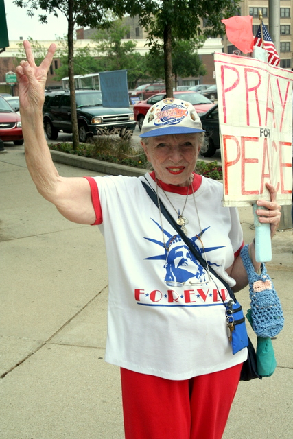 an older lady with a sign and bag on the street