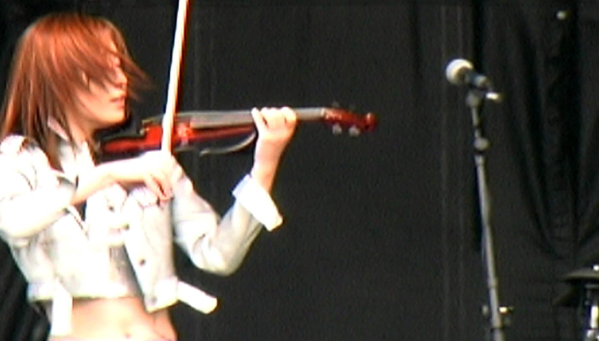 a woman with red hair holding up a violin