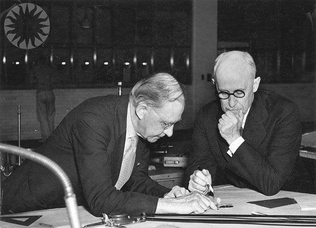 a man looks down at a clipboard while another man signs in