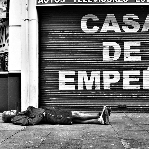 black and white pograph of a man lying on the street