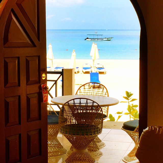 an open doorway with a table and chairs in front of the ocean