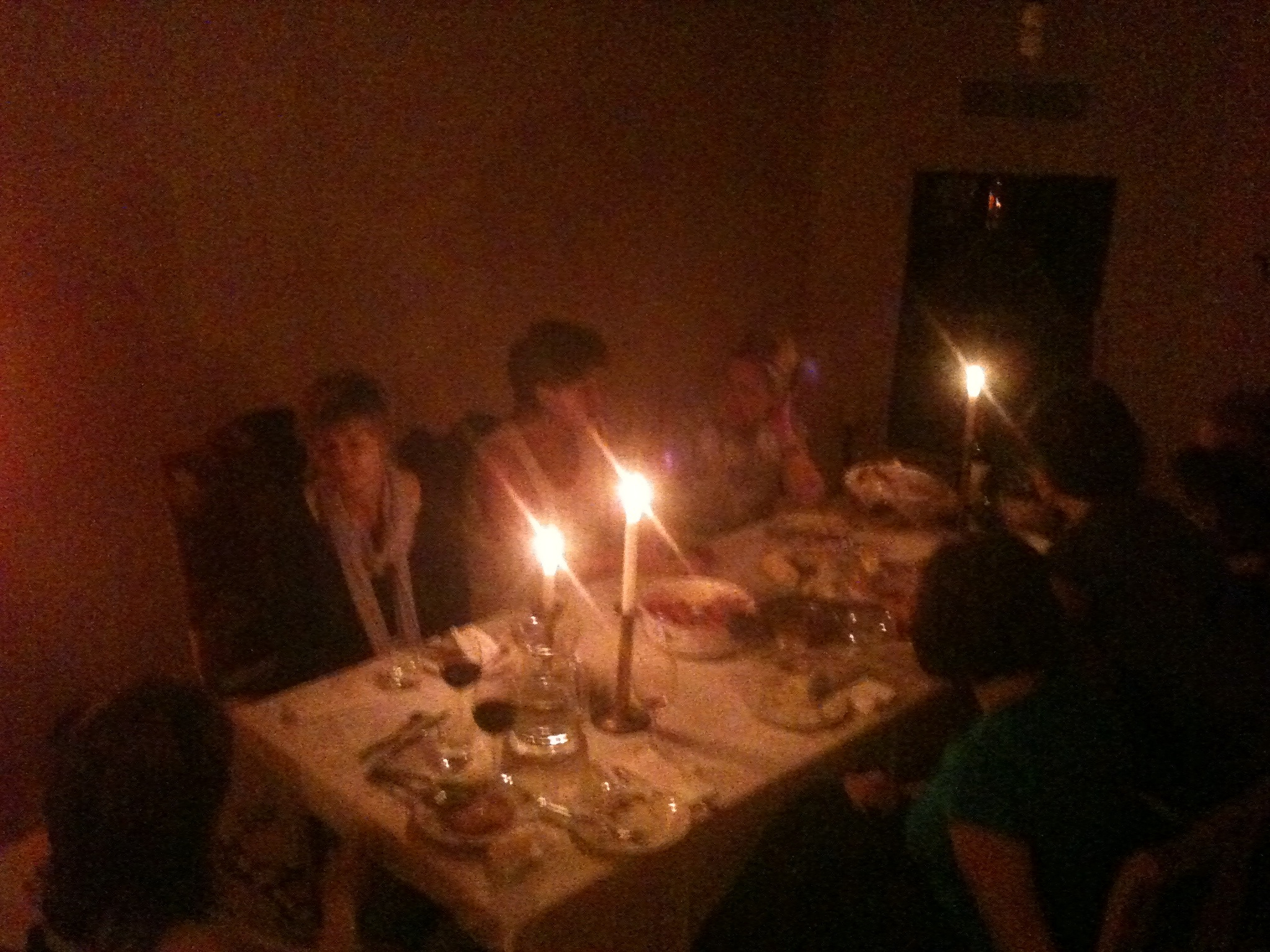 the adults gathered around the dinner table with the candles on it