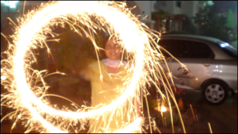 a person holding a sparkle stick near a car