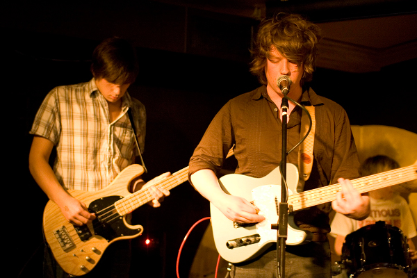 two men playing guitars in front of a microphone