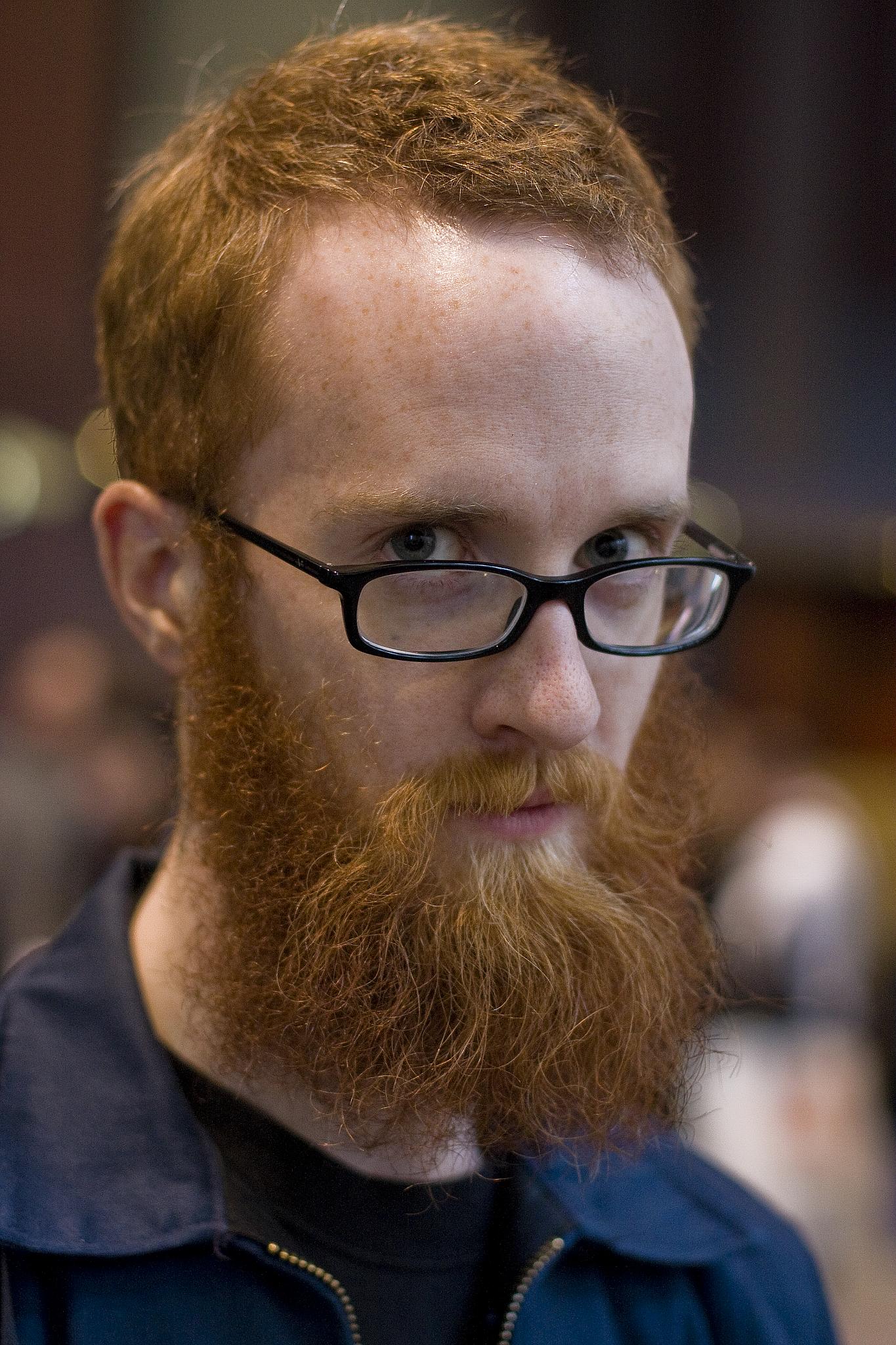 a man with red hair wearing glasses and looking at the camera