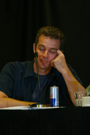 man sitting at a table listening to a microphone