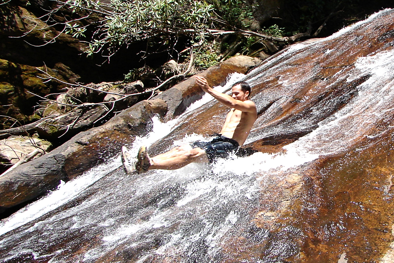 man in black swim trunks is surfing on a waterfall