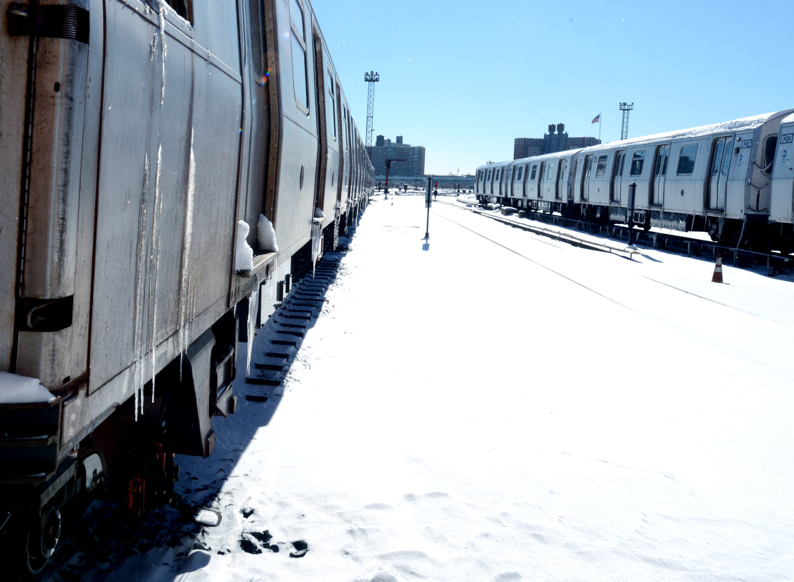 two trains side by side on a snowy railroad track