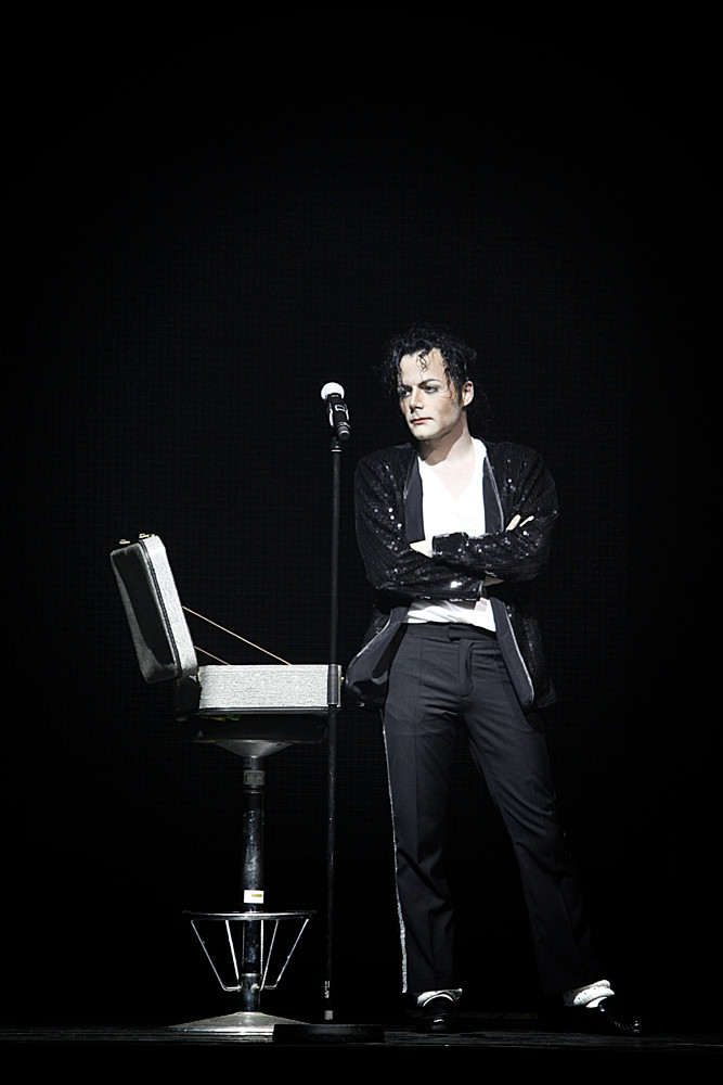 a male musician in black is performing on stage