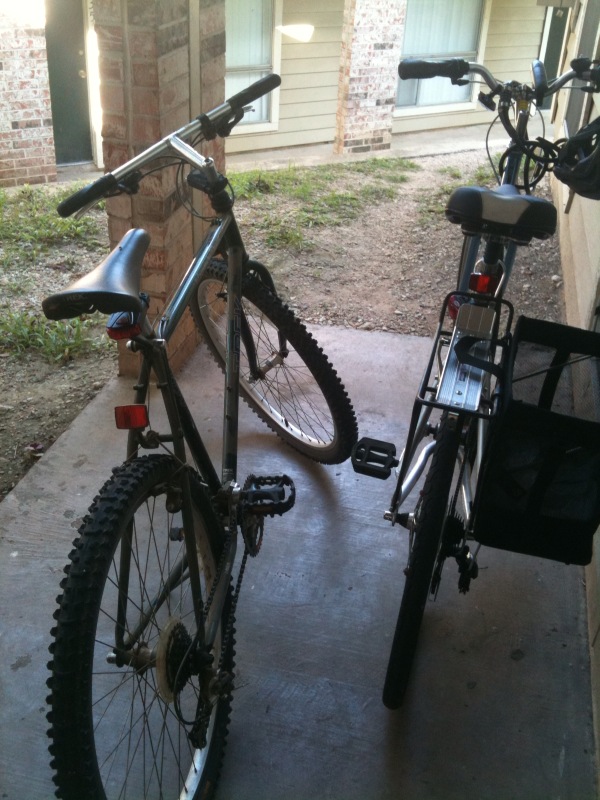 two bicycles sit side by side in a driveway