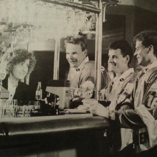 four men sit at a bar smiling