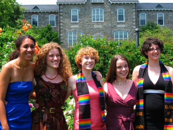 a group of women standing next to each other wearing rainbow dresses