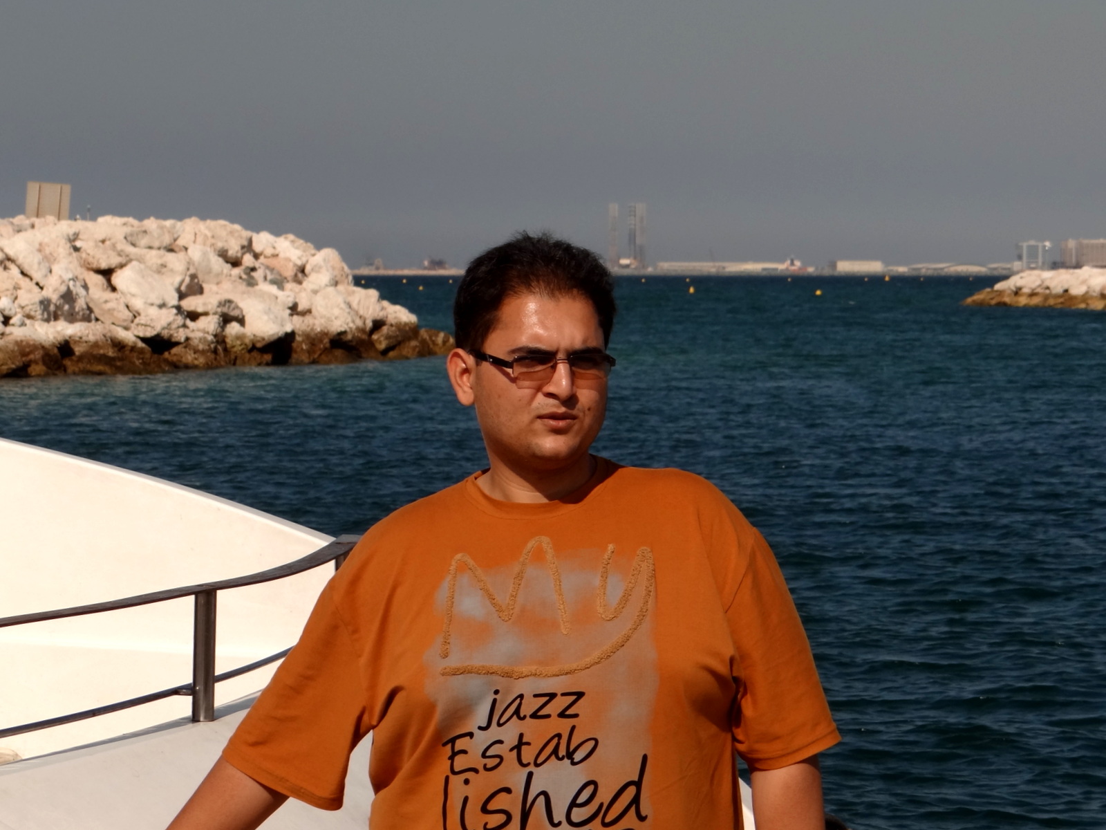 a man wearing glasses stands near the water