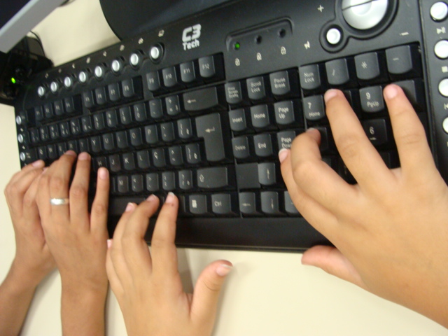 people typing on a black computer keyboard in front of their laptop