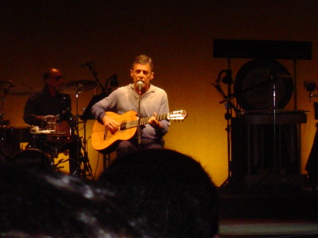 a man playing guitar in front of a microphone