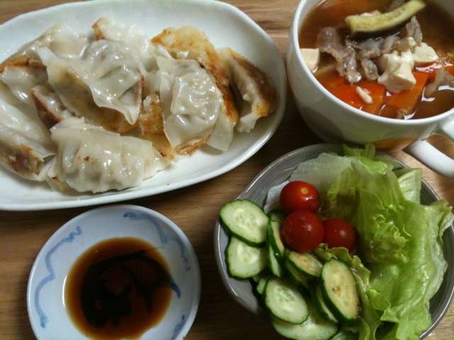 a plate of dumplings, a bowl of soup and a bowl of salad