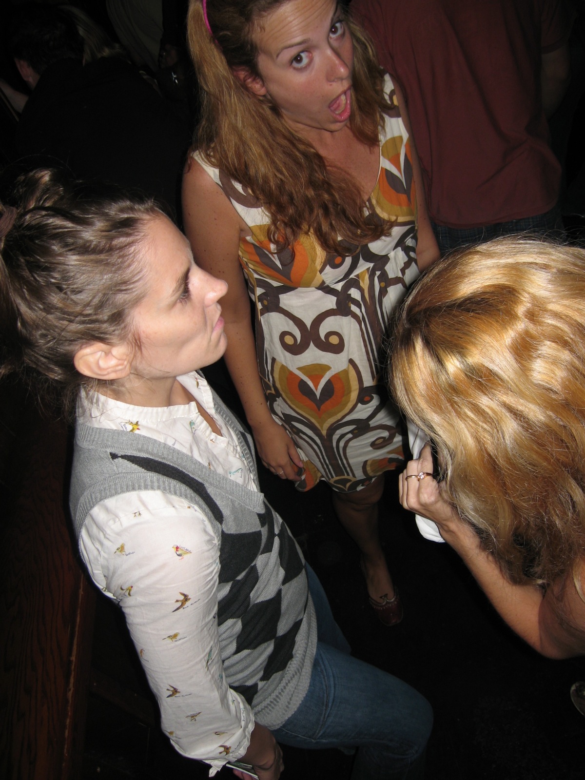 four women stand around, one is laughing and the other is looking down