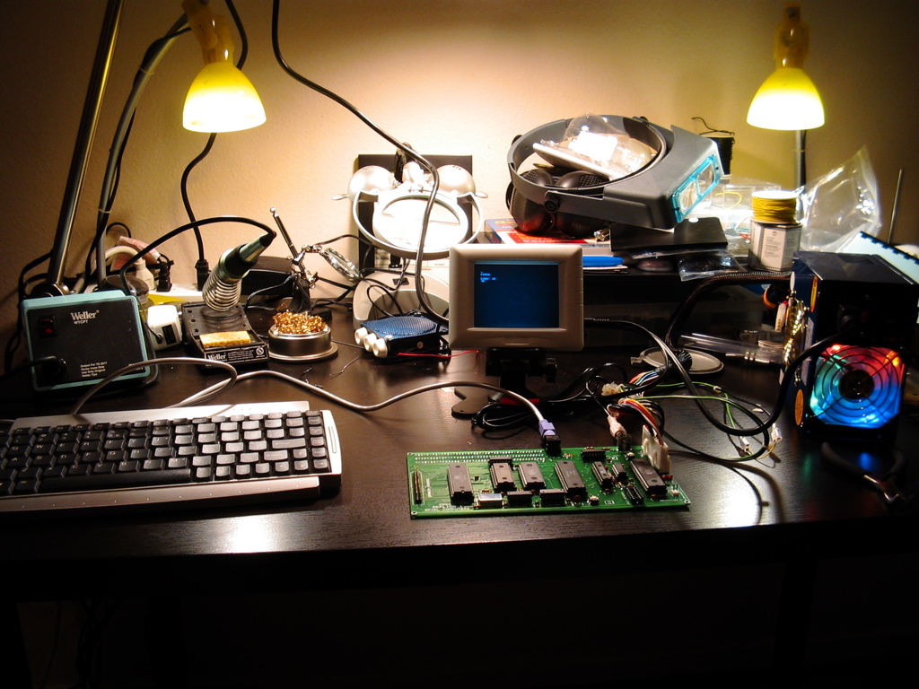 a desk with a keyboard, monitor and assorted electronics