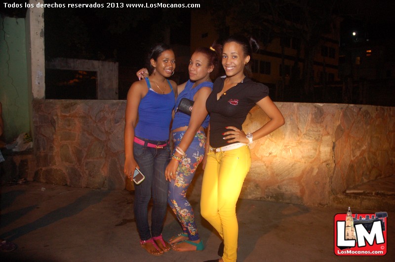 three beautiful young ladies standing together in front of a wall