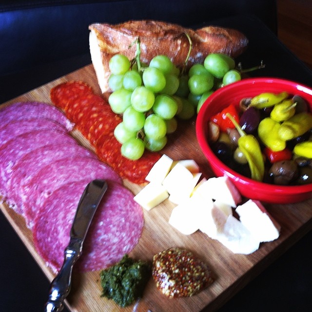 a  board with cheese, meat, and a bowl of gs