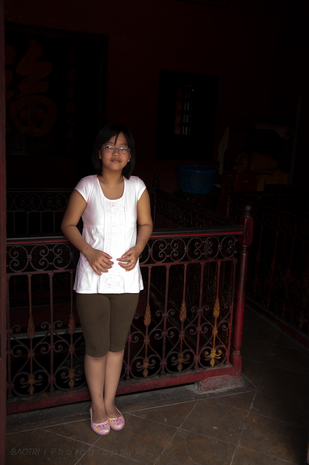 a woman standing at night next to a balcony with red railings