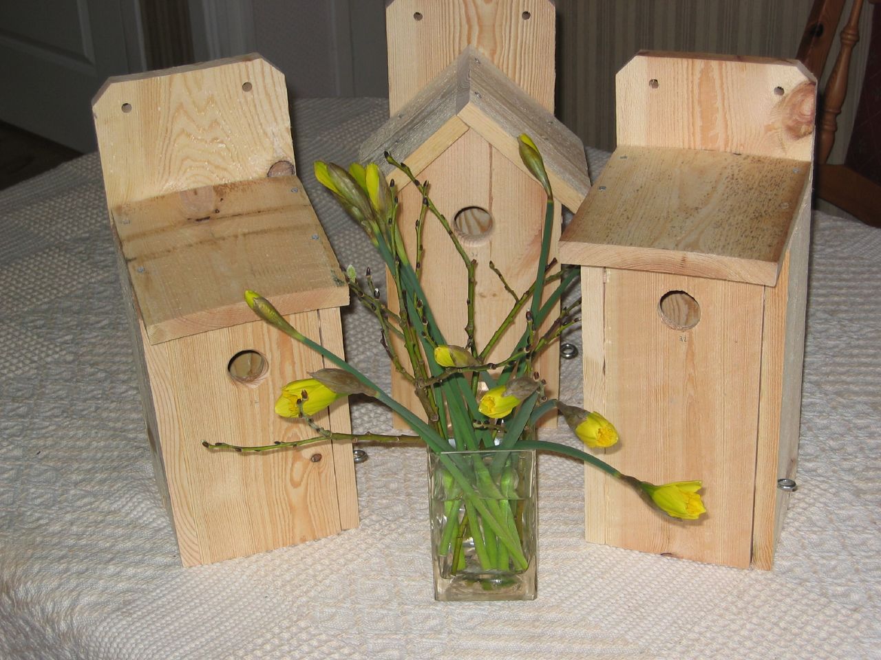 a vase of tulips are displayed with small wooden bird houses