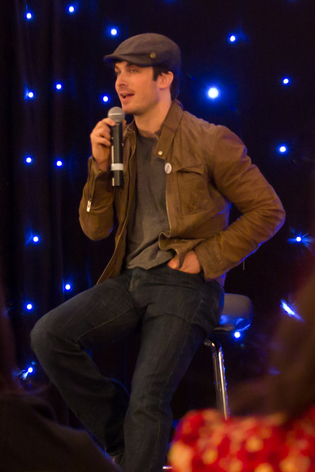 a person in a brown jacket sitting on a stool