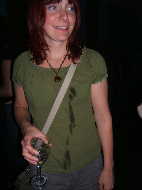 a woman with short hair smiling and holding onto a drink