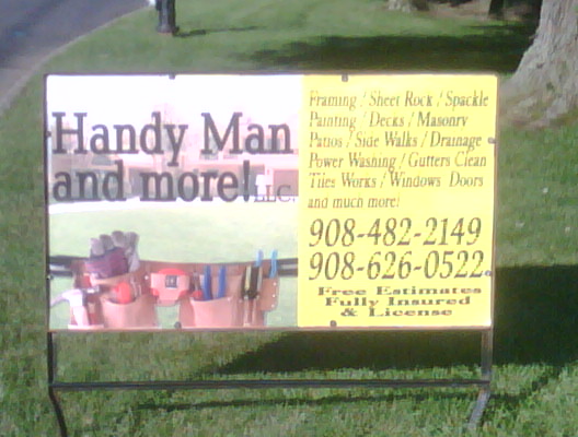 a sign for handy man and more sitting in the grass