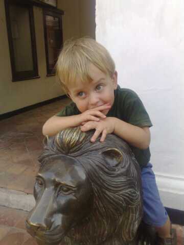 boy with arm resting on statue of bear head