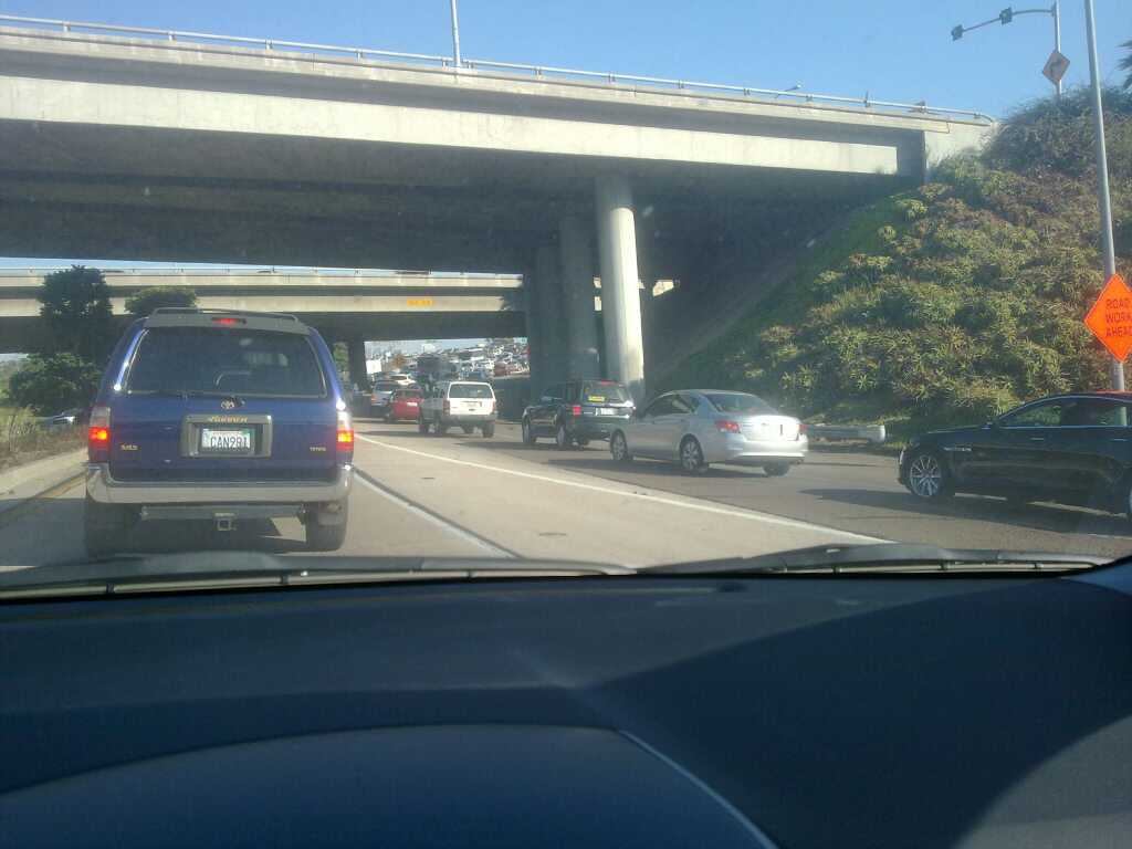 cars stopped at a red traffic light on an overpass