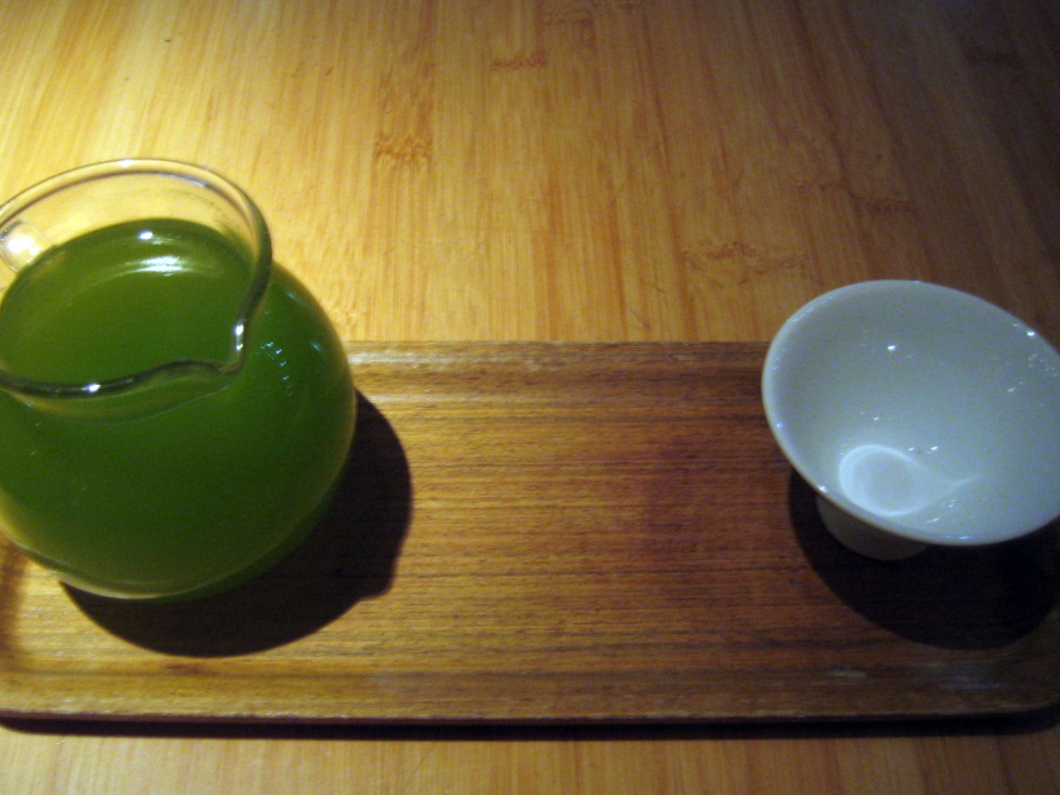 a small green glass of juice and a white bowl